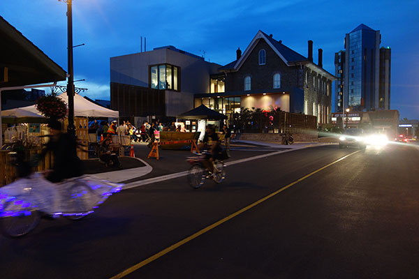 fancy bikes as part of the bike parade with the back of the museum showing and cars moving down the road