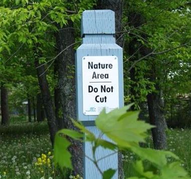 Sign on a pole stating: Nature Area, do not cut